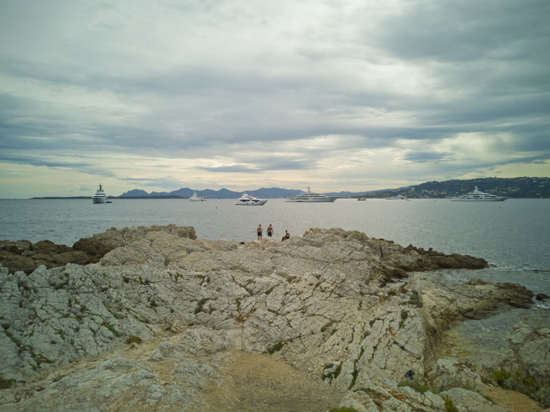 Felsstrand mit Menschen, Hafeneinfahrt | © Bert Schwarz 2019