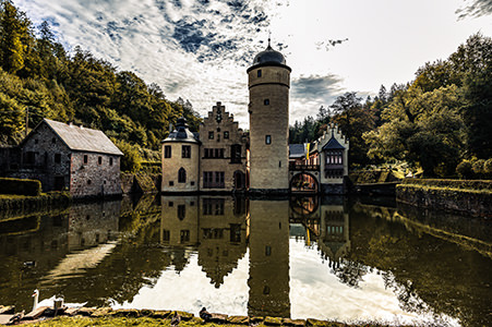 Das Wasserschloss ist von Wald umgeben und liegt hinter einem kleinen Teich | © Bert Schwarz 2024
