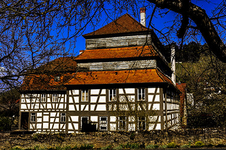 Die Papiermühle hinter Bäumen im Garten | © Bert Schwarz 2021