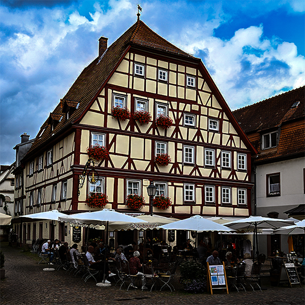 Gasthaus, Gaeste unter Sonnenschirmen | © Bert Schwarz 2025